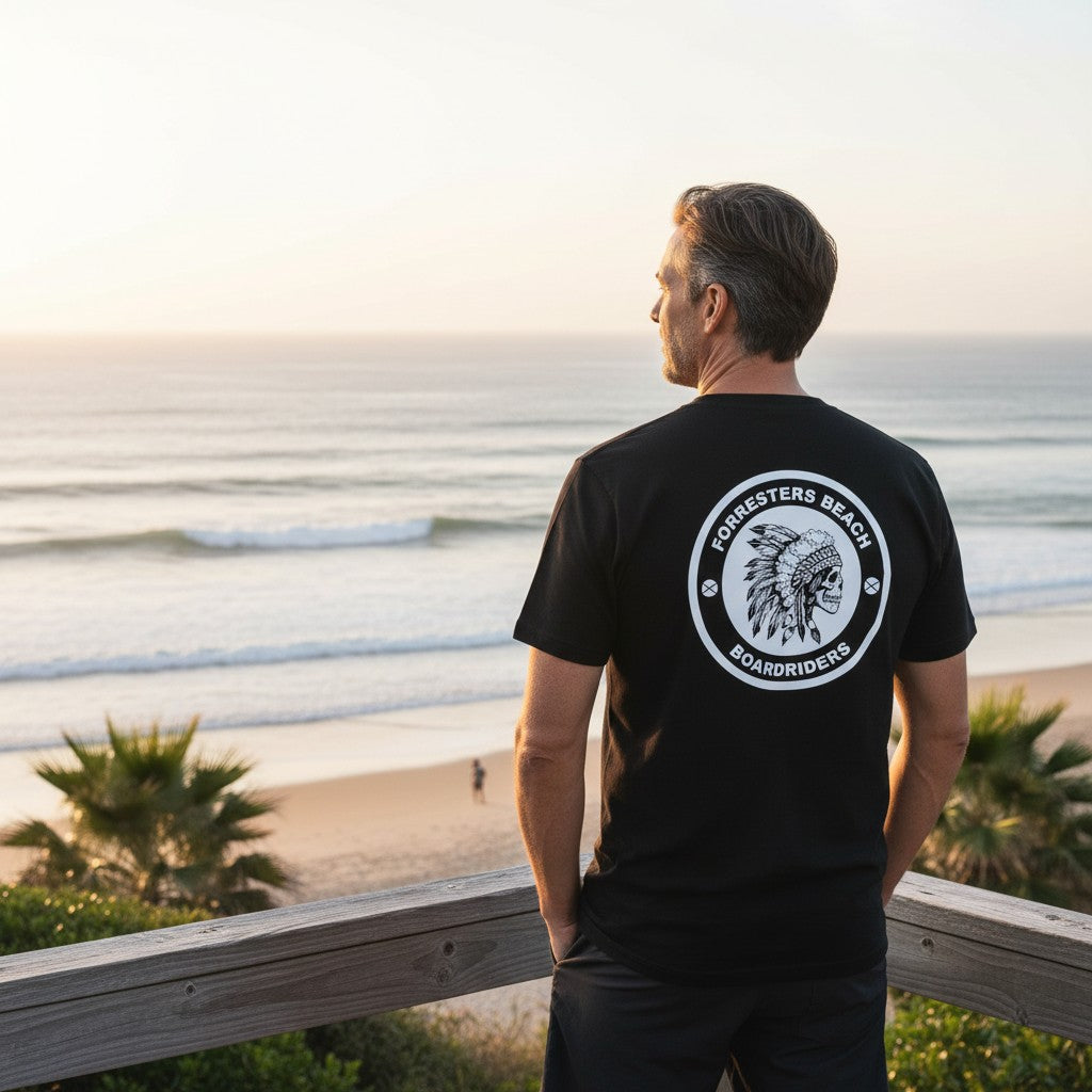 Sideliners black unisex t-shirt with Forresters Beach Boardriders skull logo back print worn by a man at the beach
