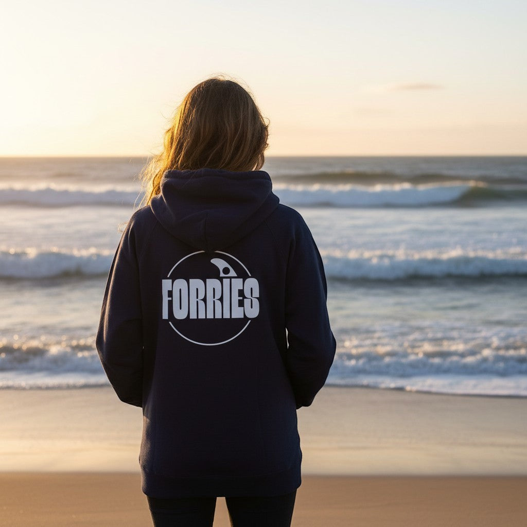 Sideliners women's navy hoodie with white Forries logo on back, worn by a woman at the beach during sunset.